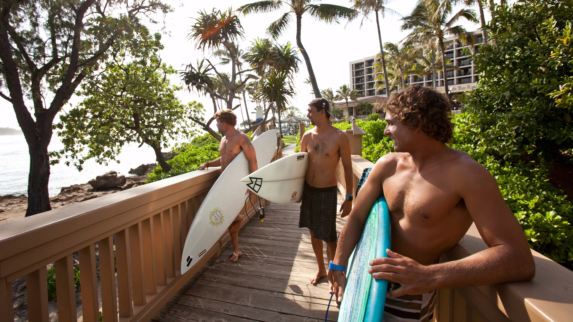 Group of 3 friends with surfboard looking out over water