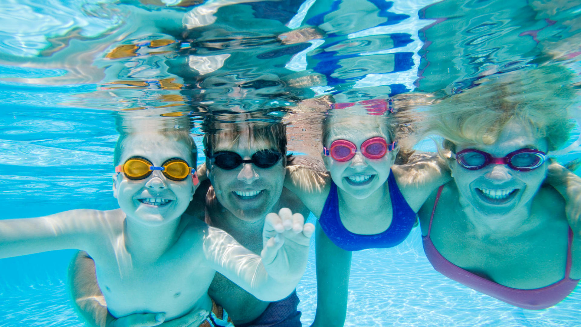 family underwater in a pool with goggles on